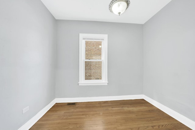 spare room featuring visible vents, wood finished floors, and baseboards