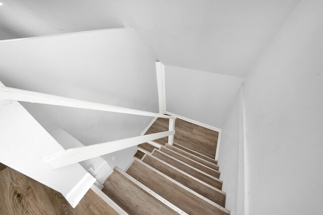 stairway featuring wood finished floors and vaulted ceiling