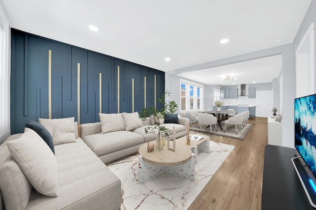 living area with recessed lighting, light wood-style floors, and a decorative wall