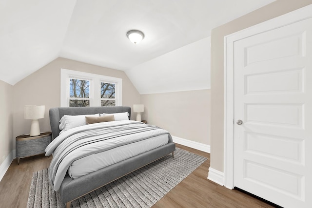 bedroom featuring baseboards, wood finished floors, and vaulted ceiling