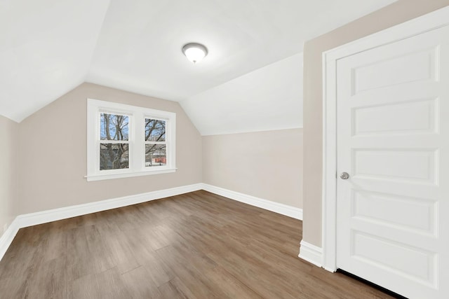 bonus room featuring baseboards, lofted ceiling, and dark wood finished floors