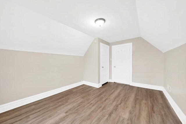 bonus room with vaulted ceiling, wood finished floors, and baseboards