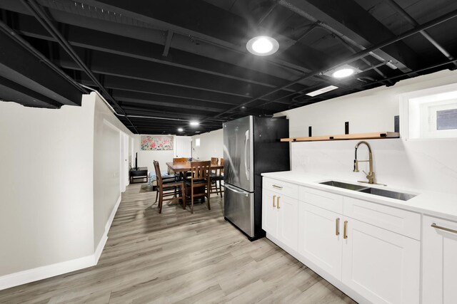 kitchen featuring open shelves, white cabinets, a sink, light wood-style floors, and freestanding refrigerator