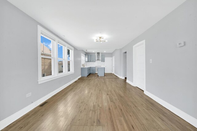unfurnished living room with visible vents, wood finished floors, and baseboards