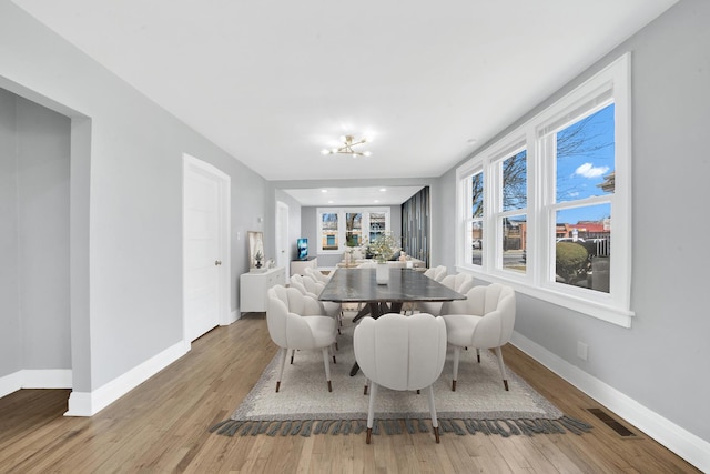 dining area featuring baseboards, visible vents, and wood finished floors