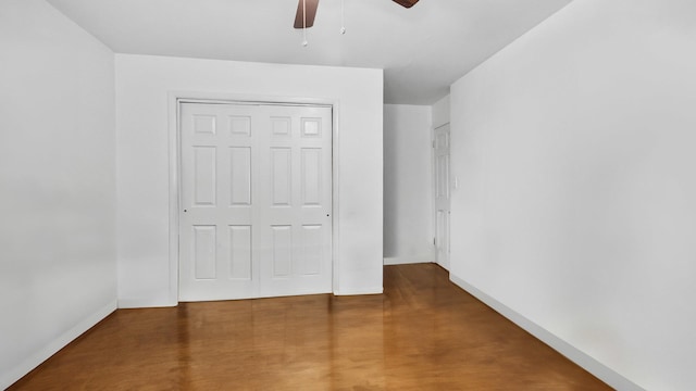 unfurnished bedroom featuring ceiling fan, finished concrete floors, baseboards, and a closet