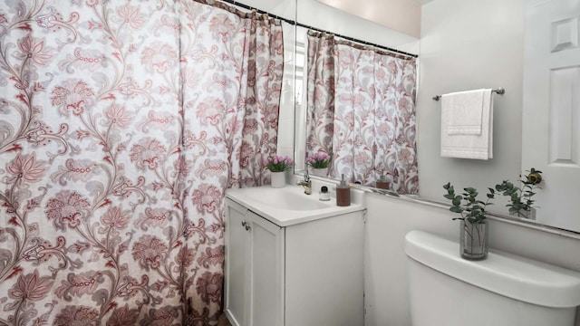 bathroom featuring curtained shower, toilet, and vanity