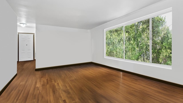 unfurnished room featuring dark wood-style floors and baseboards