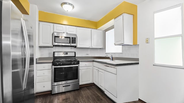 kitchen featuring dark countertops, tasteful backsplash, white cabinetry, and stainless steel appliances