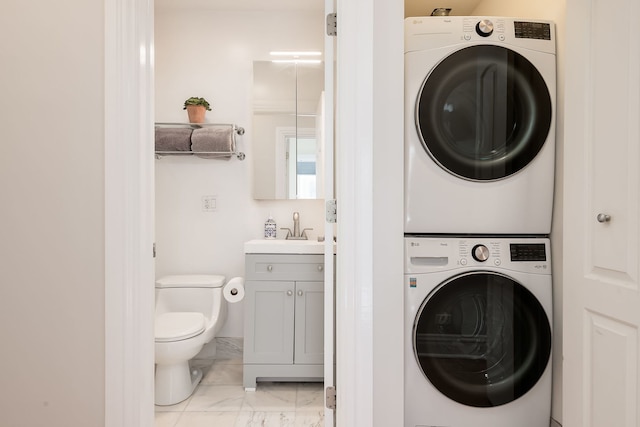 clothes washing area featuring marble finish floor, laundry area, a sink, and stacked washer and clothes dryer
