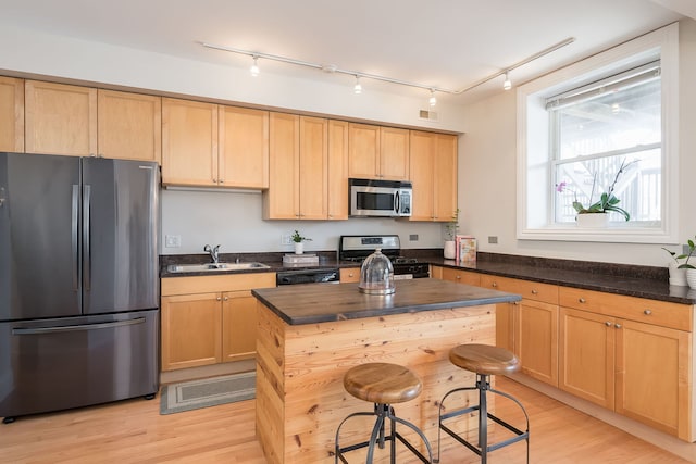 kitchen featuring stainless steel appliances, visible vents, a sink, and light wood-style flooring