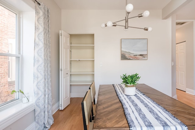 dining area featuring an inviting chandelier, light wood finished floors, baseboards, and visible vents