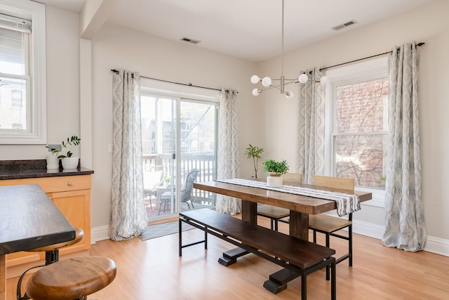 dining area featuring baseboards, light wood-style flooring, and visible vents