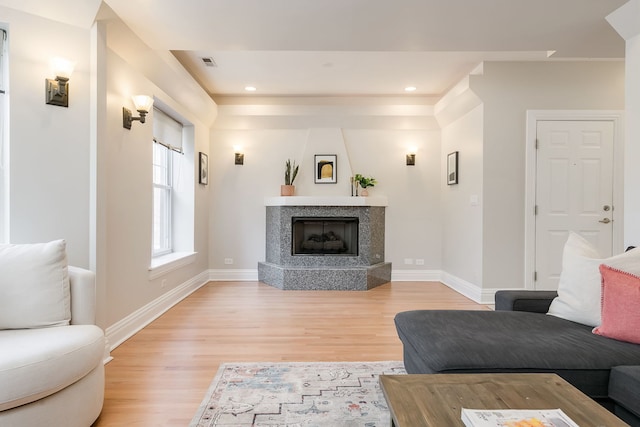 living room with baseboards, a fireplace, light wood finished floors, and visible vents