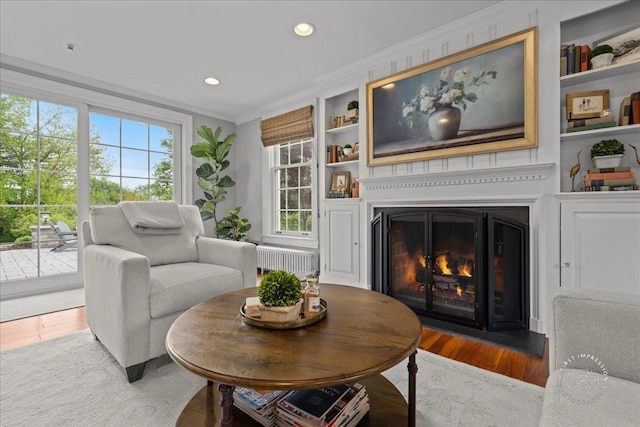 6N225 Circle Ave, Medinah, IL 60157 - living room featuring ornamental molding, a fireplace with flush hearth, radiator, wood finished floors, and built in features