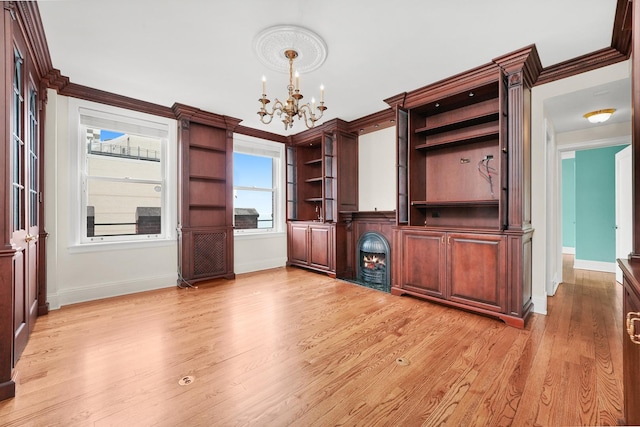 unfurnished dining area featuring baseboards, ornamental molding, a notable chandelier, and light wood finished floors