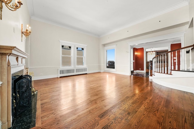 unfurnished living room with wood finished floors, stairs, radiator, ornamental molding, and a fireplace