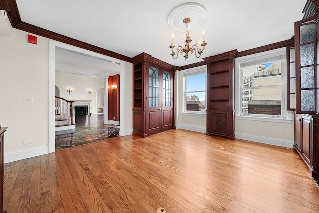 unfurnished dining area with ornamental molding, baseboards, a notable chandelier, and light wood-style floors
