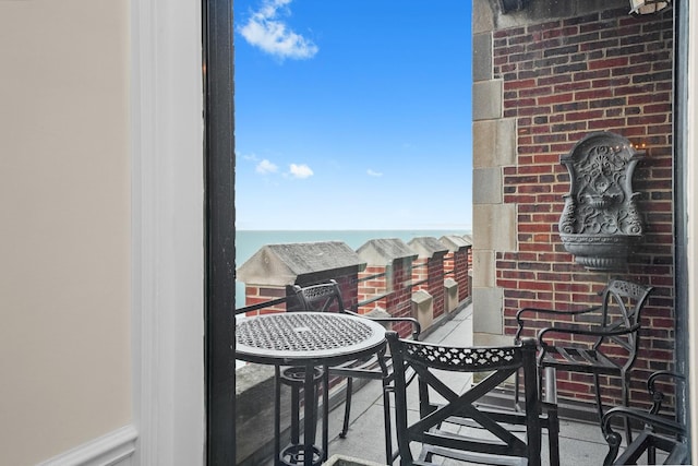 balcony with outdoor dining area and a water view