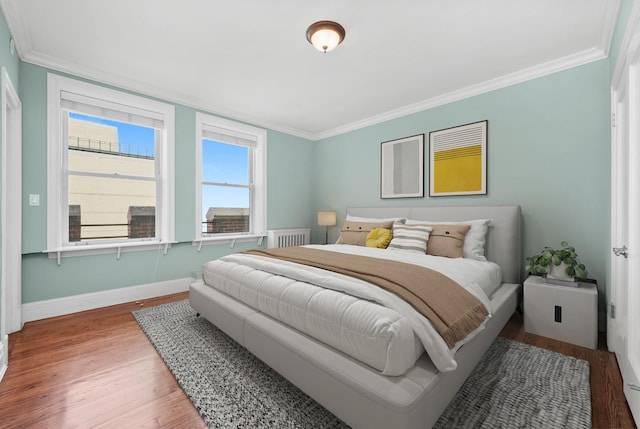 bedroom with baseboards, wood finished floors, and ornamental molding