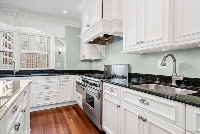 kitchen featuring high end range, white cabinets, custom exhaust hood, and a sink