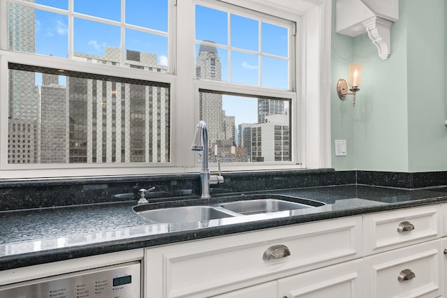 details featuring dark stone countertops, white cabinetry, a sink, dishwashing machine, and a city view