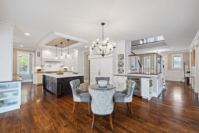 dining area featuring a chandelier, ornamental molding, dark wood finished floors, wine cooler, and recessed lighting
