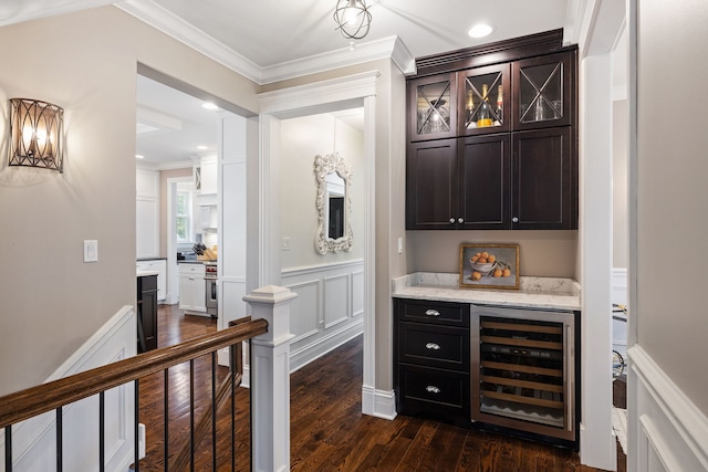 indoor dry bar featuring beverage cooler, dark wood-style flooring, and crown molding