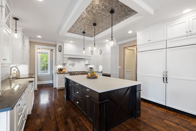 kitchen with white cabinets, ornamental molding, a tray ceiling, glass insert cabinets, and recessed lighting