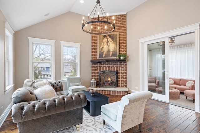 living area with a chandelier, hardwood / wood-style floors, a fireplace, high vaulted ceiling, and baseboards