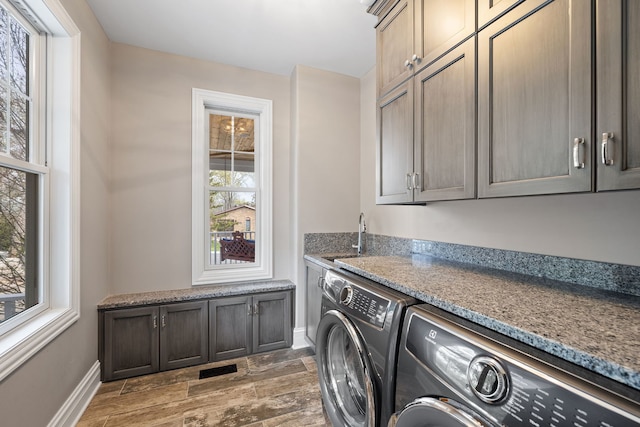 laundry room featuring washer and dryer, cabinet space, wood finished floors, baseboards, and bar
