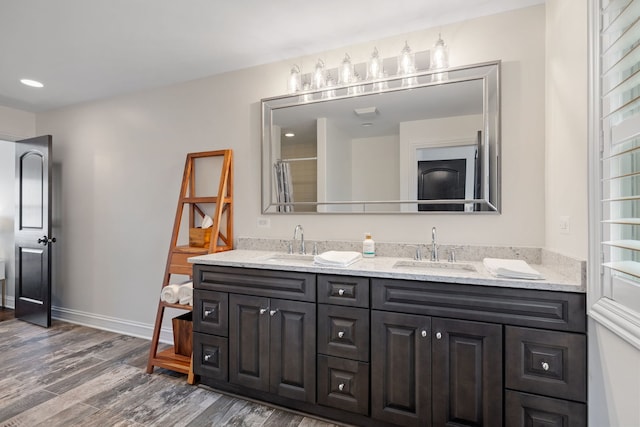 bathroom featuring wood finished floors, double vanity, recessed lighting, baseboards, and curtained shower