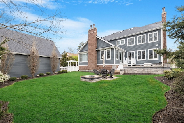 rear view of property featuring a chimney and an outdoor fire pit