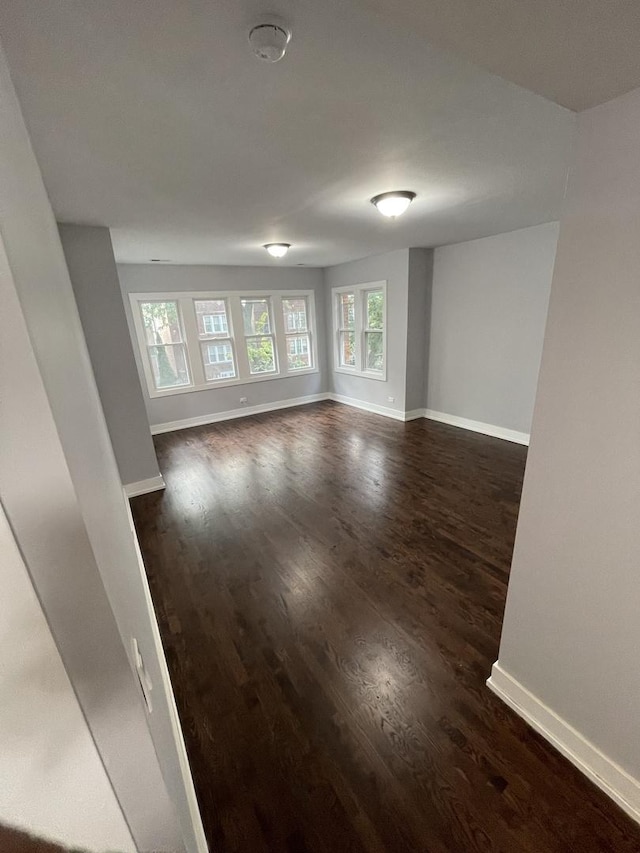 spare room featuring dark wood-style flooring and baseboards