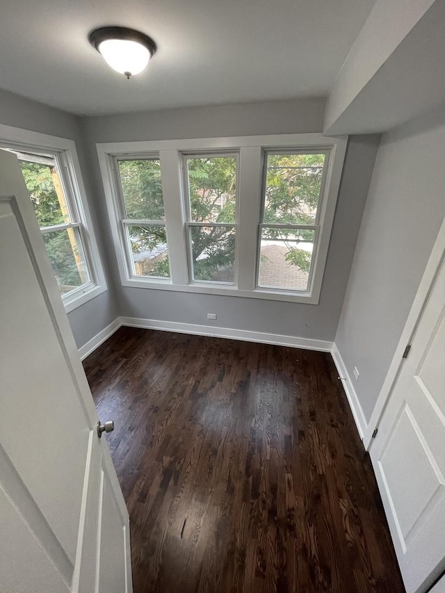 spare room with dark wood-type flooring and baseboards