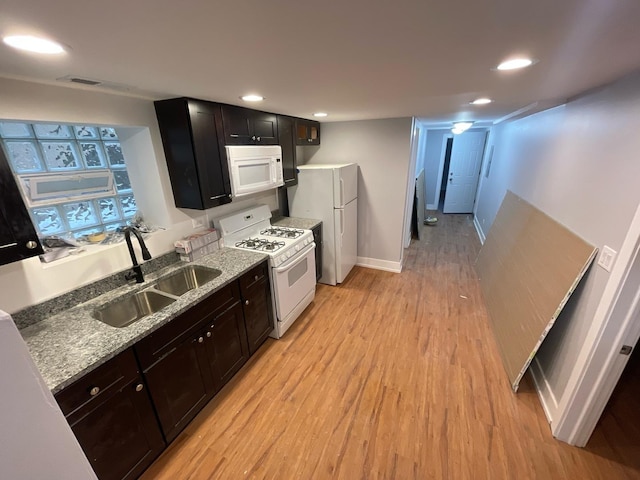 kitchen with a sink, light wood-style flooring, white appliances, and recessed lighting