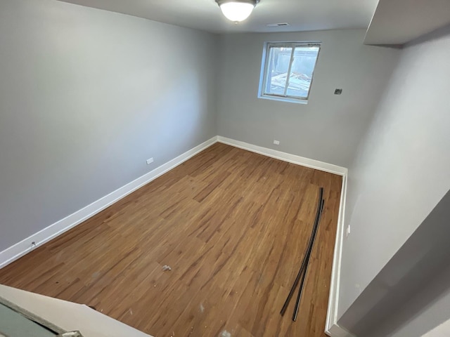 spare room with baseboards, visible vents, and wood finished floors
