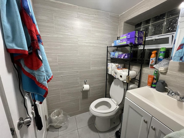 bathroom with tile patterned flooring, toilet, tile walls, and vanity