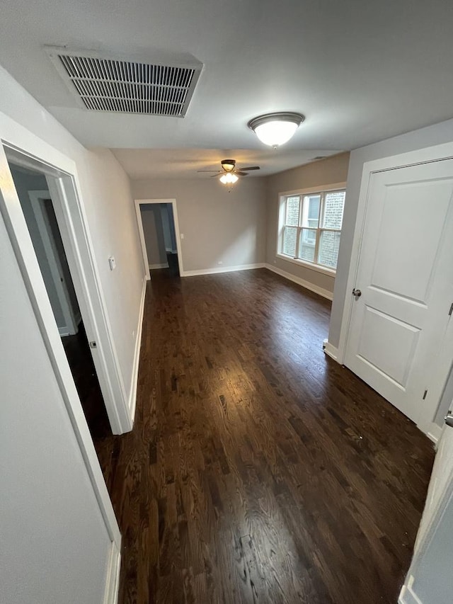 spare room with baseboards, dark wood-style flooring, visible vents, and a ceiling fan