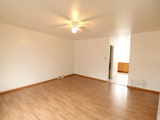 empty room with light wood-type flooring, visible vents, a ceiling fan, and baseboards