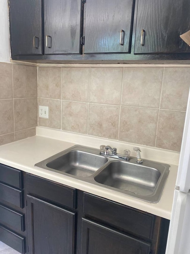 kitchen featuring light countertops, a sink, freestanding refrigerator, and tasteful backsplash