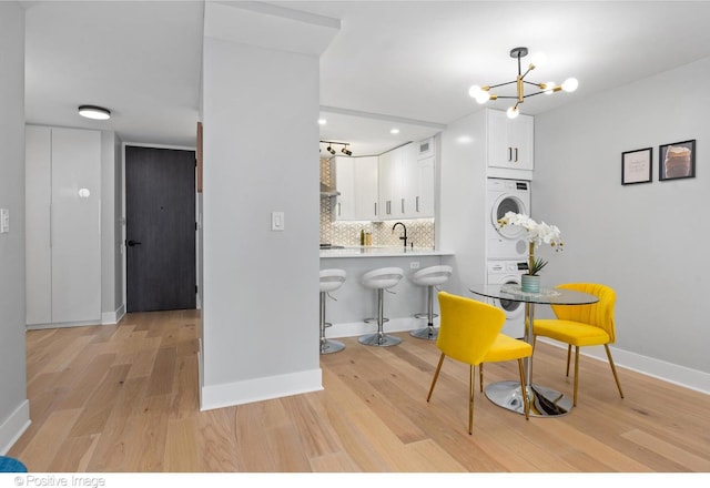 1030 N State St Unit 21K, Chicago, IL 60610 - dining space with stacked washer / drying machine, an inviting chandelier, light wood-style flooring, and baseboards