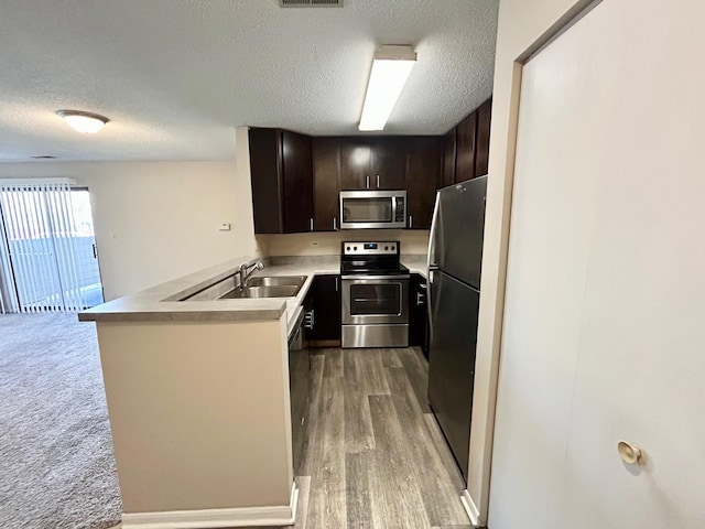 1915 N Hicks Rd Unit 105, Palatine, IL 60074 - kitchen with dark brown cabinetry, stainless steel appliances, light countertops, a sink, and a textured ceiling