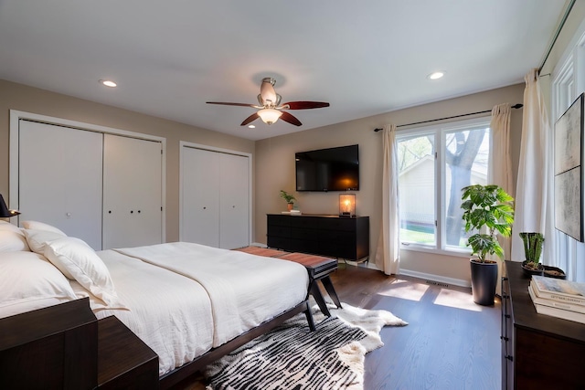 bedroom featuring recessed lighting, baseboards, two closets, and dark wood-style floors