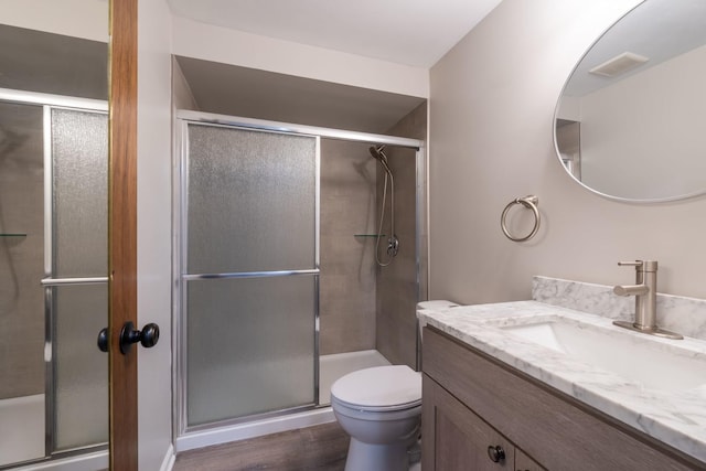 bathroom with vanity, visible vents, wood finished floors, toilet, and a shower stall