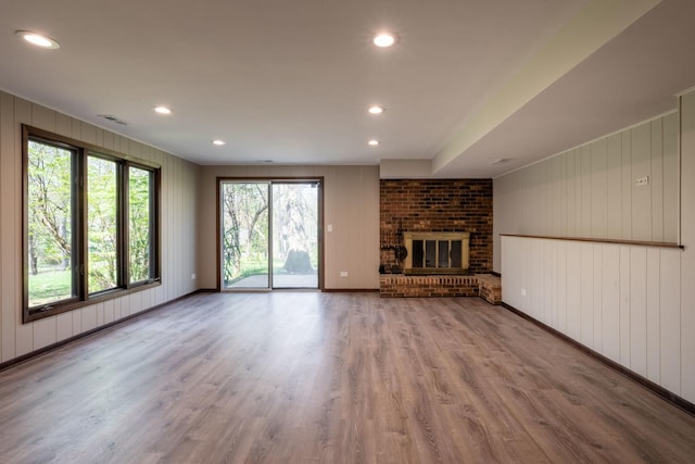 unfurnished living room with visible vents, recessed lighting, a brick fireplace, and wood finished floors
