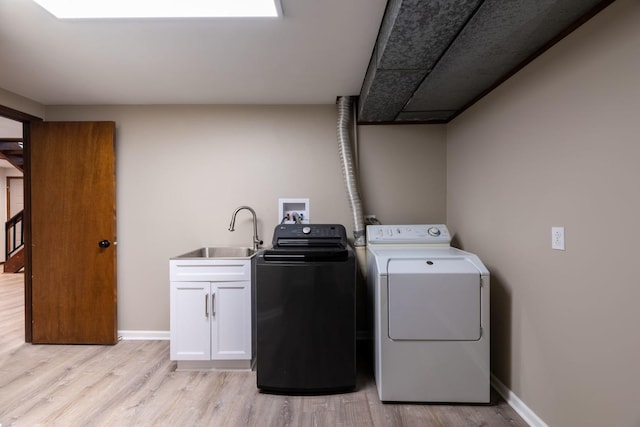 laundry room with a sink, light wood-style floors, cabinet space, and washing machine and clothes dryer