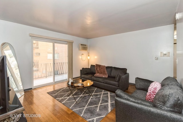 living area with an AC wall unit and wood finished floors