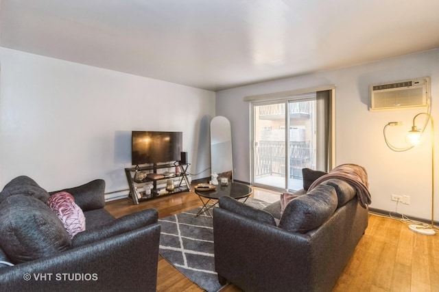 living area featuring baseboard heating, baseboards, a wall unit AC, and wood finished floors