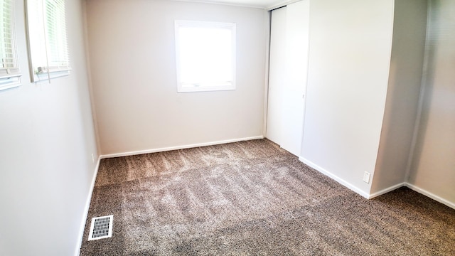 carpeted empty room featuring baseboards, plenty of natural light, and visible vents